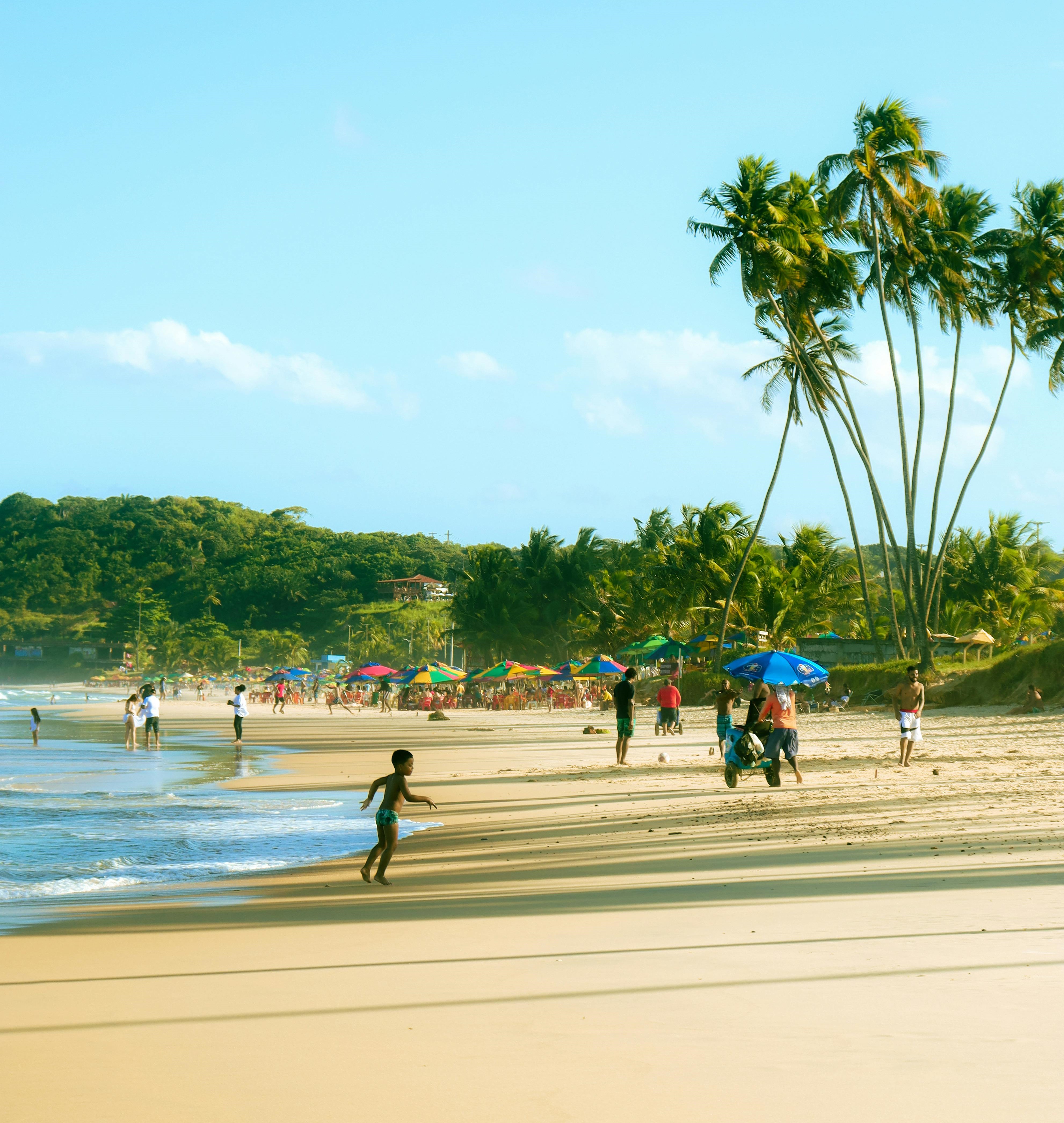 Praia do Recife - PE, com vários banhistas se banhando e aproveitando o sol e o mar azul