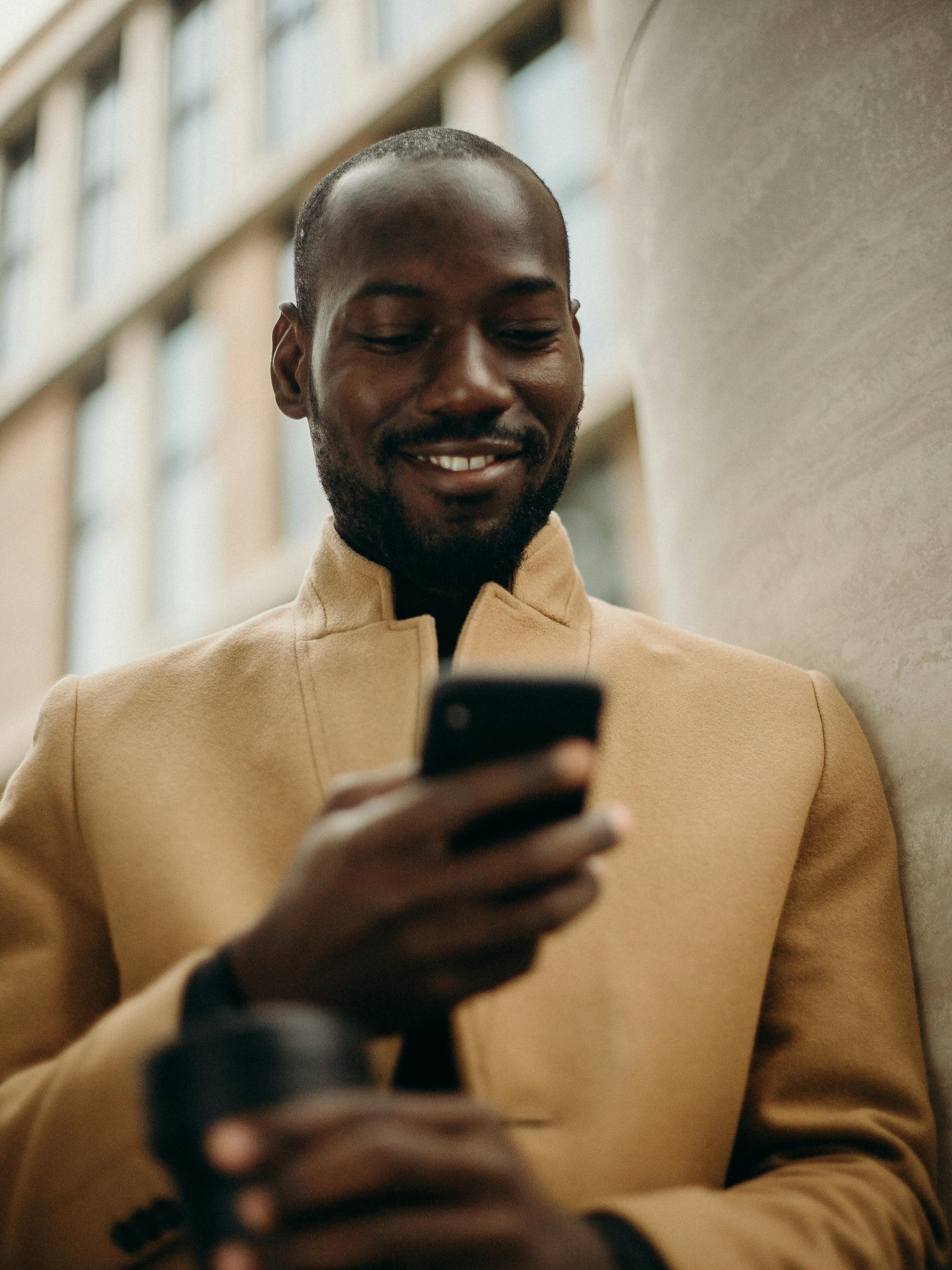 Homem segurando seu telefone e sorrindo